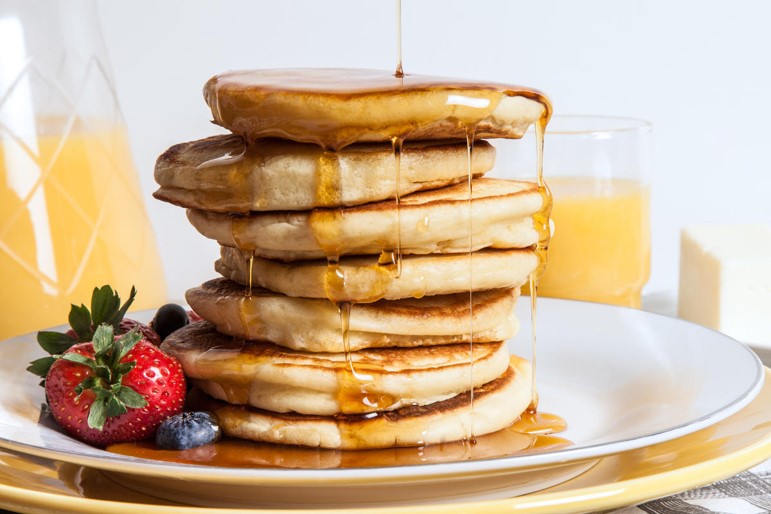 Pile of pancakes with syrup pouring over
